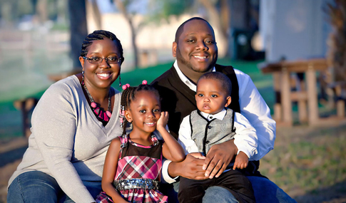 A family with young children sits outside in a park.