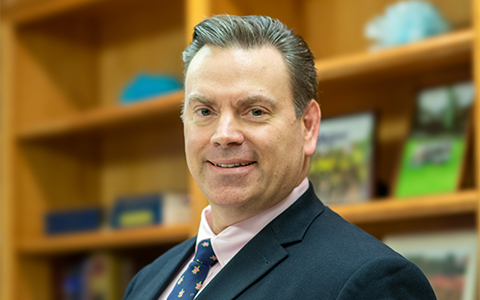 Brian Perry in the office wearing a dark blue suit and tie.