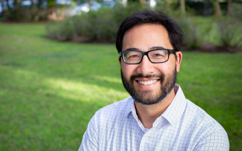 A photo Curt Ostrodka smiling and standing casually in a yard. 