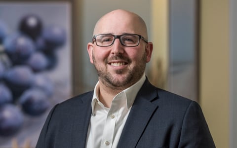 Lou Bekofsky in a dark gray suit and cream shirt.