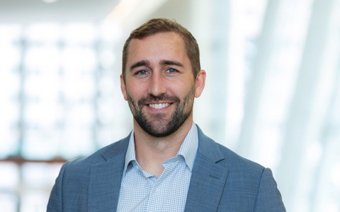 Seth at the office, wearing a white shirt and tan blazer.