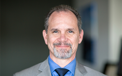 Man wearing a gray suit and tie in an office setting