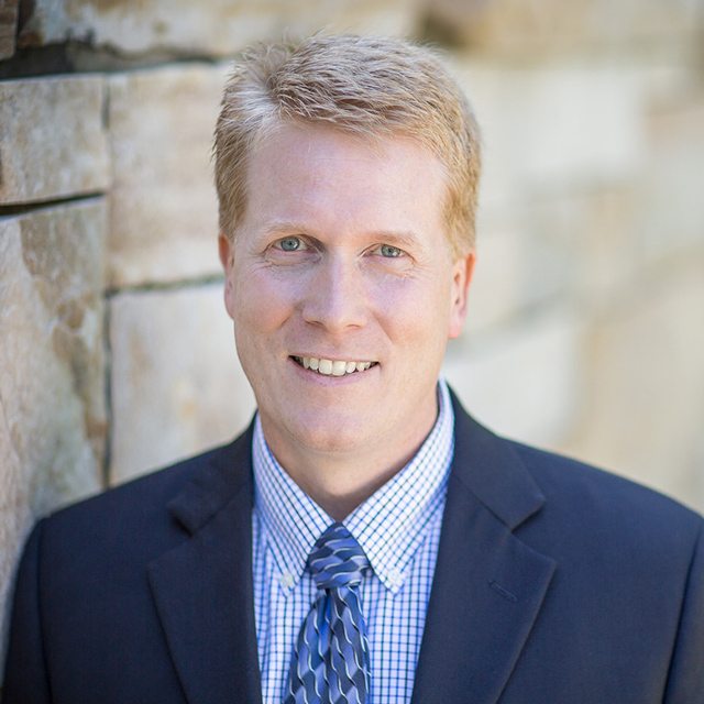 Mike Williard smiling in a blue suit.