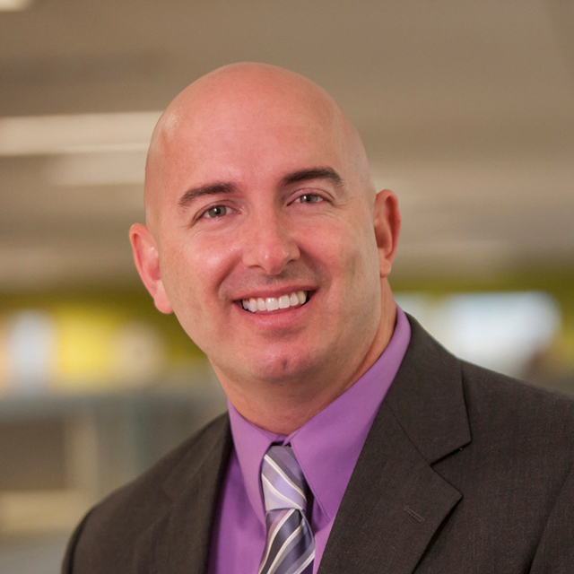 Shawn Tofte with a purple shirt and striped tie