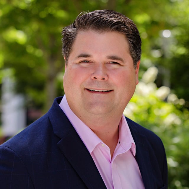 Wayne Robinson in a pink shirt and navy blue jacket.