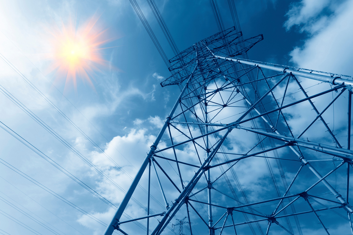 A transmission line against a cloudy sky with the sun breaking through.