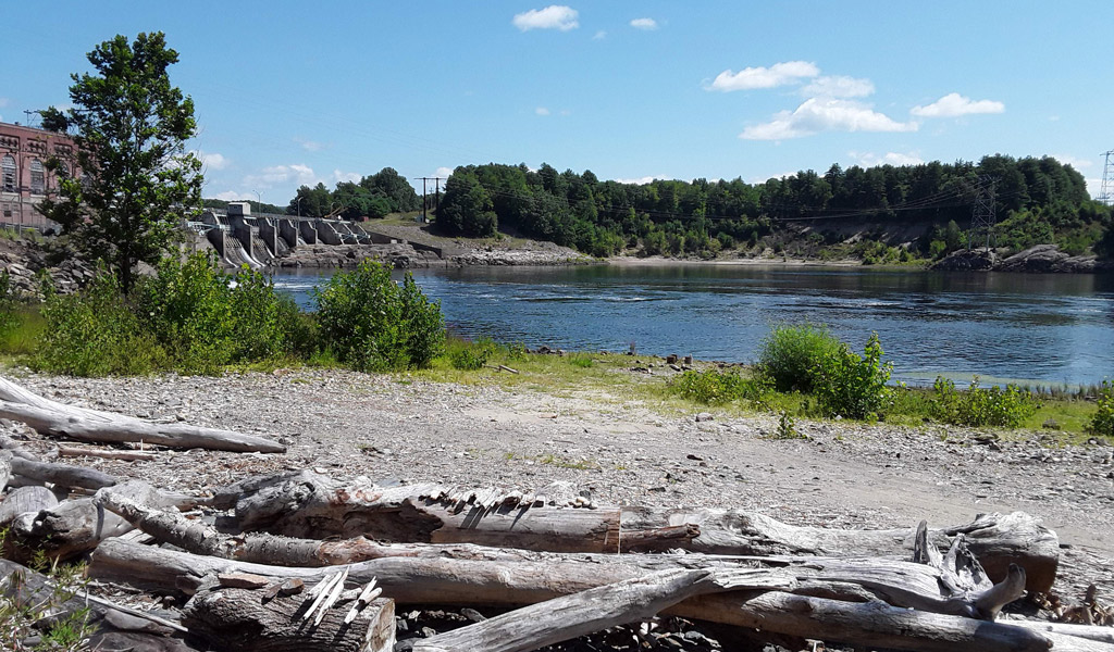 Power lines crossing a river by a dam.