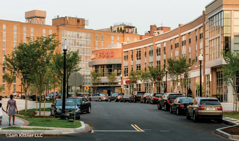 A street with cars parked in front of a curving building.