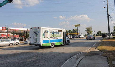 A fleet of small buses with Connect Douglas signage on the body of the vehicle