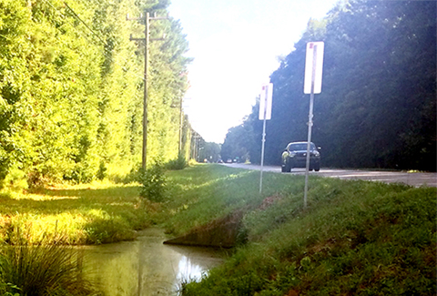 A car drives along a rural road next to a waterway in Georgia.