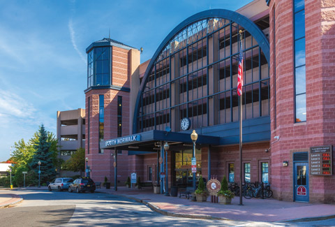 The westbound entrance to the South Norwalk train station and its parking garage, with cars parked outside.