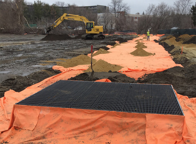 Grate over soil and construction vehicle.