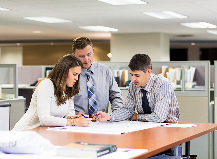 Engineering team members in office reviewing documents.