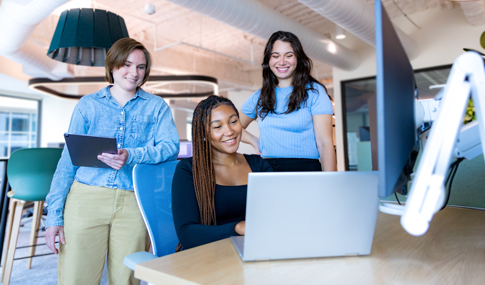 3 women collaborating and working on a laptop.