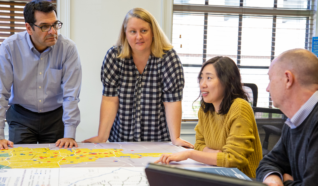 VHB team members gathered around a table discuss items on a map