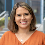 A woman with short brown hair wearing an orange shirt