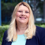 A smiling woman with blonde hair and a blue shirt