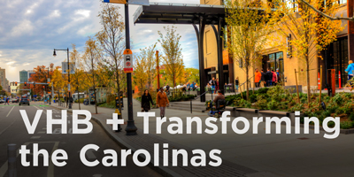 City streetscape with bike lanes, bus lanes, wide sidewalks, seat walls, and pedestrians.