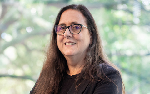 Denise wearing glasses and a blazer in an office setting.