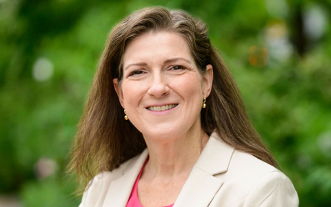 Jenny Fleming smiles at the camera in a pink shirt and beige blazer.