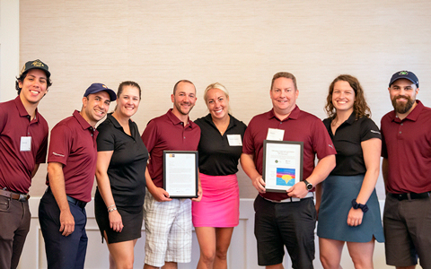 Eight smiling VHBers in golf attire.