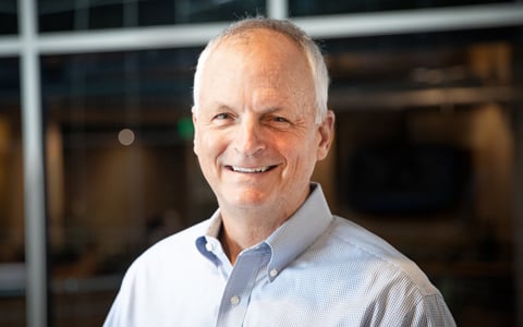 John Classe wears a light blue shirt and stands outside a building