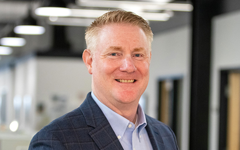 Headshot of John Hapkiewicz in an office wearing business attire.