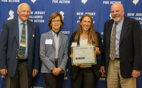 Four people smiling with an award.