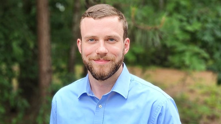 Charlie Townsend smiles at the camera wearing a blue button up shirt.