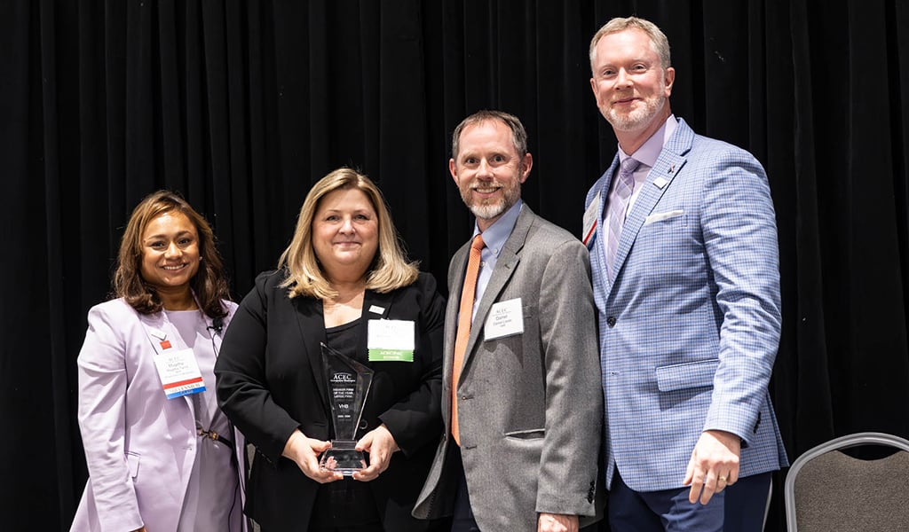 Michelle Cavucci and Dan Lovas stand on stage at the ACEC MW conference to receive the Member Firm of the Year award. 