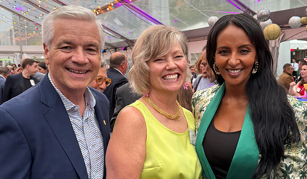 Three people smiling at the camera at an event.