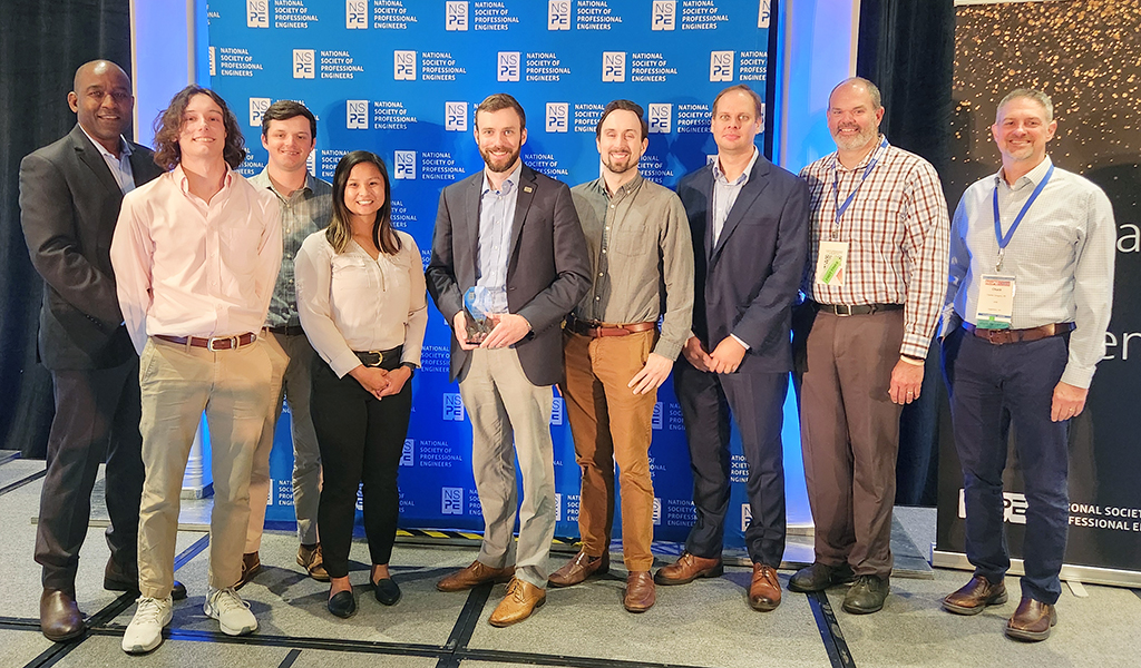 Charlie Townsend and a group of VHBers smiles at camera with the NSPE award.