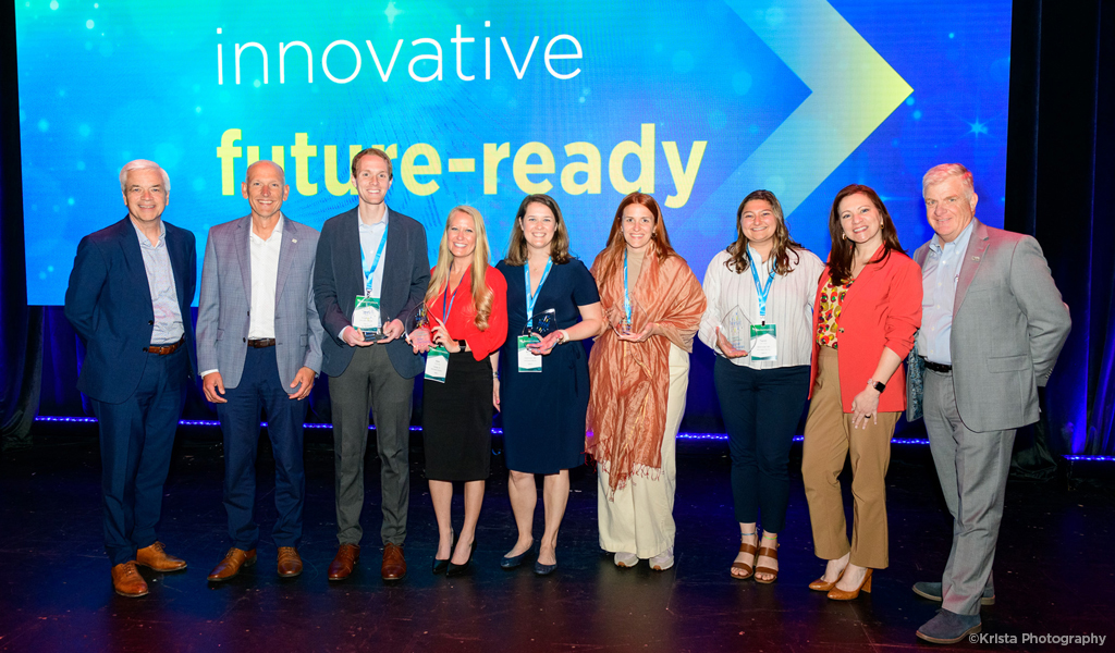 Group shot of the 2023 Culture Champions RISE Award winners on stage and smiling in front of the words innovative and future-ready on the screen.