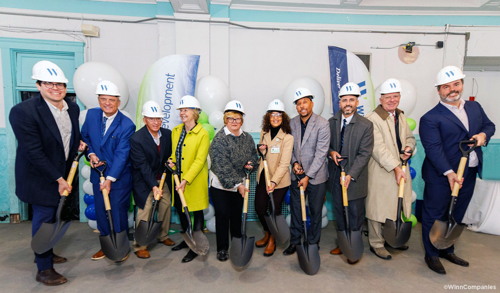 People smiling with hard hats and shovels.