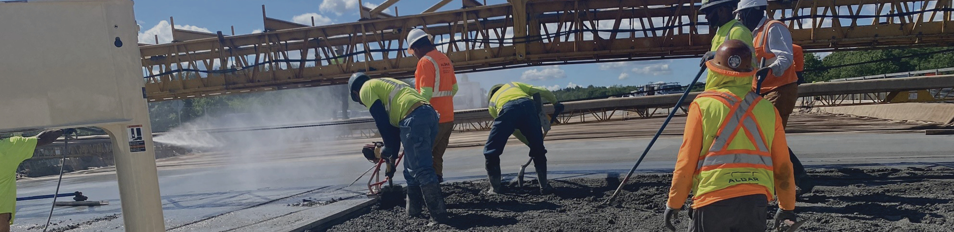 Seven men on a highway construction site pouring concrete