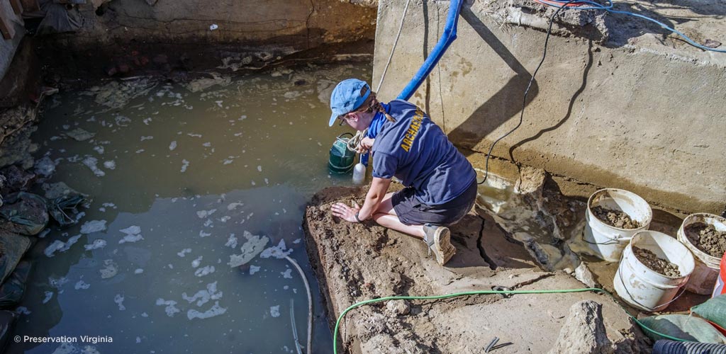 An archaeologist pumps water from one of the dig sites at Jamestown after a rain event