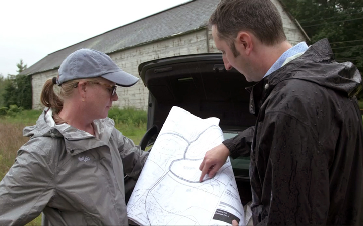 A man and woman looking at a map outside.