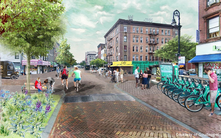 A downtown area with pedestrians an bicyclists enjoying the day.