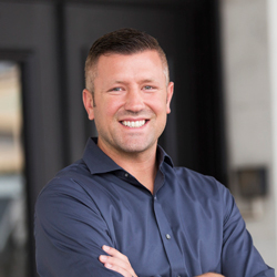 Justin Dufresne standing outside the office in a blue shirt