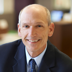 Bill Ashworth in the office wearing a dark suit and tie